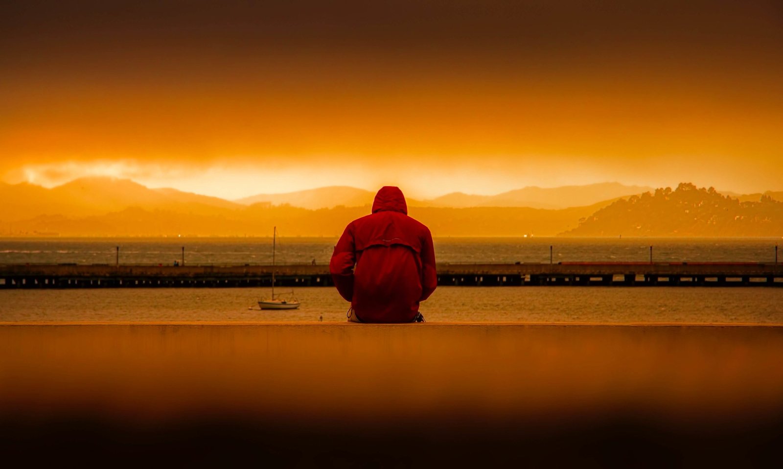 person-wearing-red-hoodie-sitting-in-front-of-body-of-water-636164 (1)